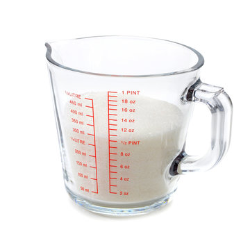 Granulated sugar in measuring cup isolated on white background