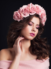 Obraz na płótnie Canvas Portrait of young beautiful dark haired woman with magnificent rose wreath and gentle makeup on black background