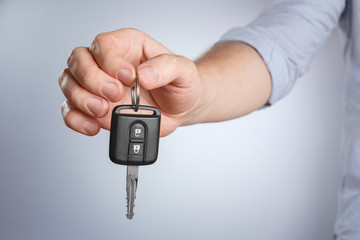 Hand suggesting car key on gray background