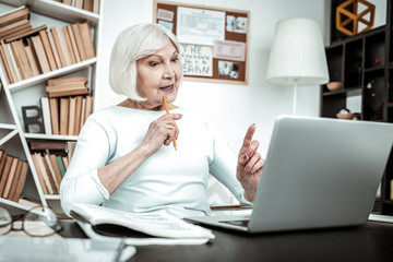 Creative mature female person sitting at her workplace