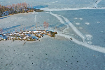 Aerial view of frozen lake. Winter scenery. Landscape photo captured with drone above winter wonderland.