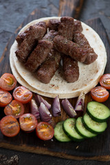 Barbecued cevapcici or skinless beef sausages with tortilla wraps and vegetables, vertical shot