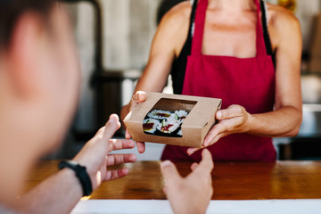 Crop vendor giving sushi to customer