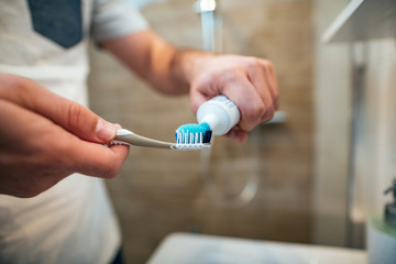 Dental health care concept. Close-up of man squeezes toothpaste on the toothbrush.
