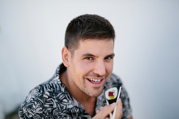 Cheerful man eating sushi