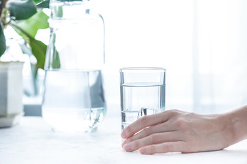 glass cup and carafe with water and ice on a white table
