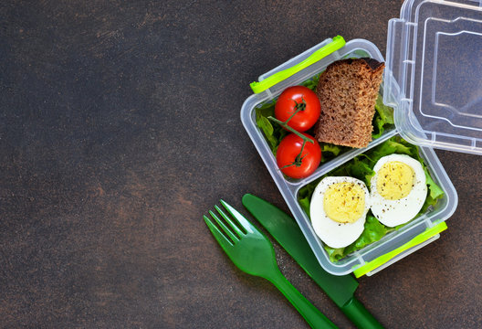 Lunch box with egg, tomato, salad and sandwich. View from above.