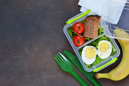 Lunch box with egg, tomato, salad and sandwich. View from above.