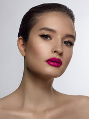 Close-up of the beauty of the female face with a classic evening make-up. Smooth black arrows on the eyelids, long eyelashes and pink lips. Beauty and cosmetology. Clean face skin