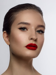 Close-up of the beauty of the female face with a classic evening make-up. Smooth black arrows on the eyelids, long eyelashes and red lips. Beauty and cosmetology. Clean face skin