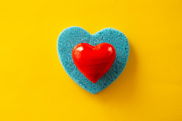 Beautiful blue and red hearts. Kinetic sand heart shape, over yellow background. Creative heart and love concept.