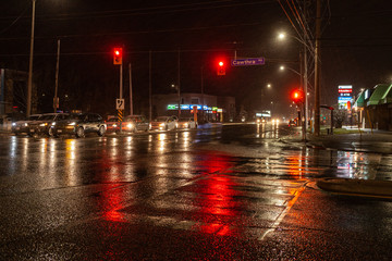 Fototapeta premium Toronto, CANADA - December 4th, 2019: Dramatic rainy night with empty streets and reflecting traffic lights in city suburbia roads