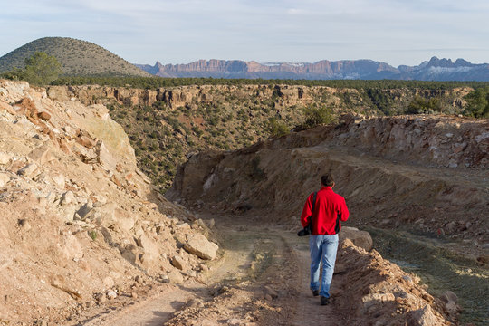 Lone man walks down dirt road near Zion National Park