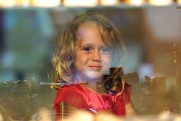 Beautiful little girl looks in the window of a shop in OIA, and makes funny faces