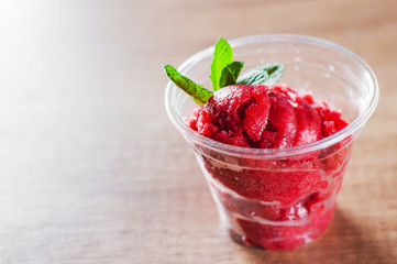 Strawberry Sorbet with red wine in a plastic cup with mint leaf
