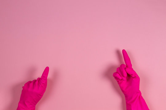 Woman Hands With Rubber Gloves Points Upwards With Finger, Over Pink Background