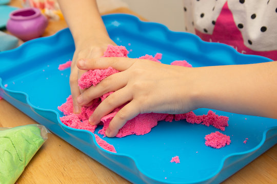 Creative play for children. Education and parenting. Children playing with pink motion sand.