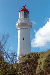 Fototapeta na wymiar White and red lighthouse in blue sky