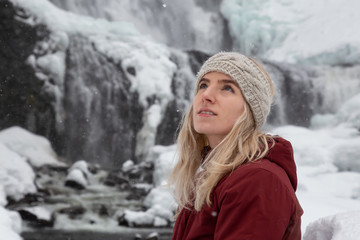 Blonde Caucasian Girl is enjoying the beautiful Canadian Winter Scenery during a snowy day. Taken in Alexander Falls, near Whistler and Squamish, North of Vancouver, BC, Canada.