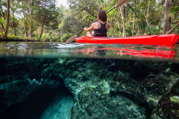 Over and Under picture of a girl kayaking in a lake near an underwater cave formation. Taken in 7...