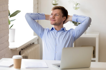 Satisfied businessman relaxing leaning back with hands behind head, enjoying break at workplace, happy man thinking about successful business project, strategy, finish work with laptop, dreaming