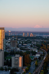 Fototapeta na wymiar Aerial view of a modern city with Mount Baker in the Background during a vibrant sunset. Taken in Metrotown, Burnaby, Vancouver, BC, Canada.