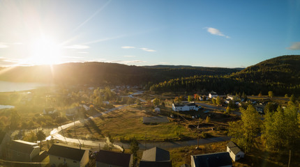 Aerial view of a small town on a rocky Atlantic Ocean Coast during a bright sunny sunrise. Taken in Little Bay, Newfoundland, Canada.