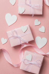 Pink valentine gift with white hearts on a pastel pink background