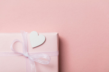 Pink valentine gift with white hearts on a pastel pink background