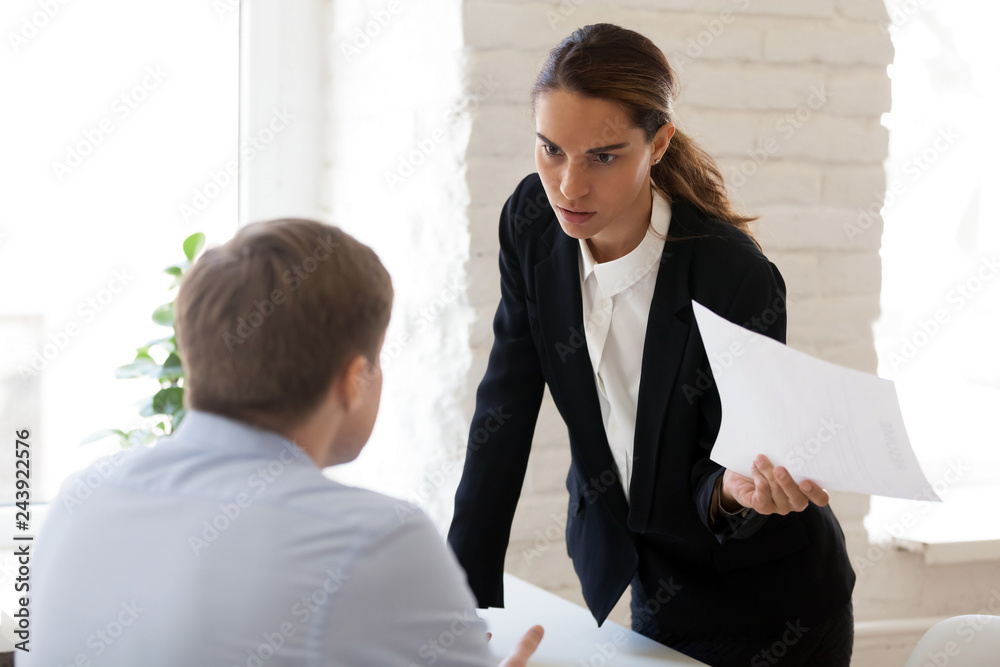 Wall mural serious businesswoman blaming employee for mistake in paper document, financial report, dissatisfied