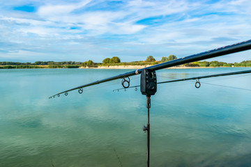 View of two fishing rods on stands with electronic lights on the background of a beautiful green lake.