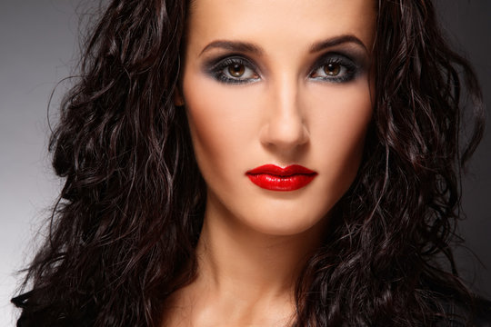 Portrait of young beautiful woman with curly hair and smoky eye make-up