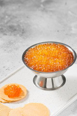 Red caviar in a metal bowl on a grey table