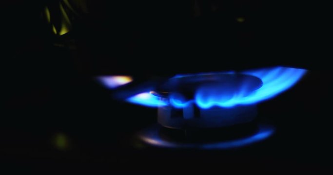 Blue flames of a gas in gas cooker. Fire on stove in dark.
