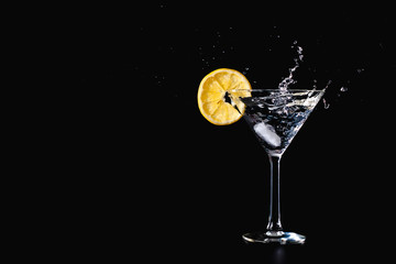 Cocktail water drink splash in the glass with lemon Isolated on black