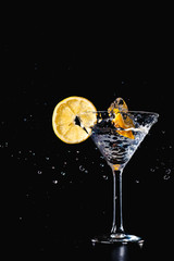 Cocktail water drink splash in the glass with lemon Isolated on black