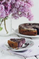 Homemade blueberry pie on a white wooden table next to a vase of