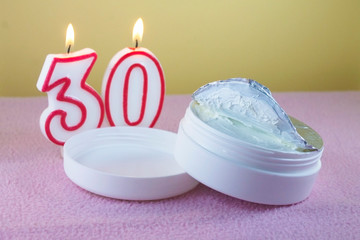 Fototapeta na wymiar tube of cream on the background of candles with number thirty