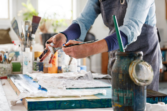 Midsection of female artist painting in studio