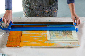 Hands of creative woman artist painter working using masking tape and art supplies in her studio