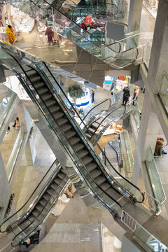 Many escalators in the high-rise shopping center. Escalators intersect. Escalators that go up and down. Moving staircase in a large mall. Multi-storey shopping center.