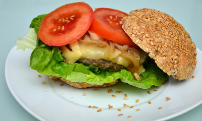Gesundes Sandwichbrötchen mit Cheeseburger, gebratenen Zwiebeln und Tomatenscheiben