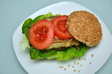 Gesundes Sandwichbrötchen mit Cheeseburger, gebratenen Zwiebeln und Tomatenscheiben