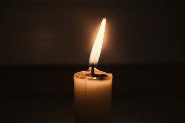 Burning candle on dark background