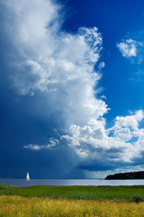 Fototapeta na wymiar Sailboat and big thunder cloud. Stormy weather approaching.