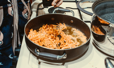 Carrots are fried in a pan