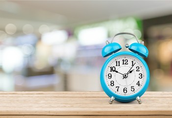Naklejka premium Blue Retro alarm clock on wooden table on wall background