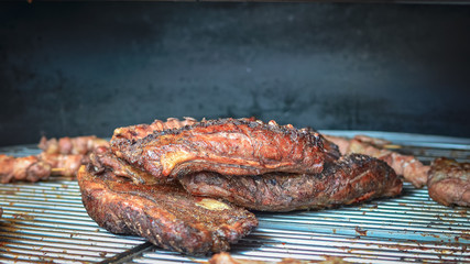 Raw meat and ribs roasted on fire on dark background.