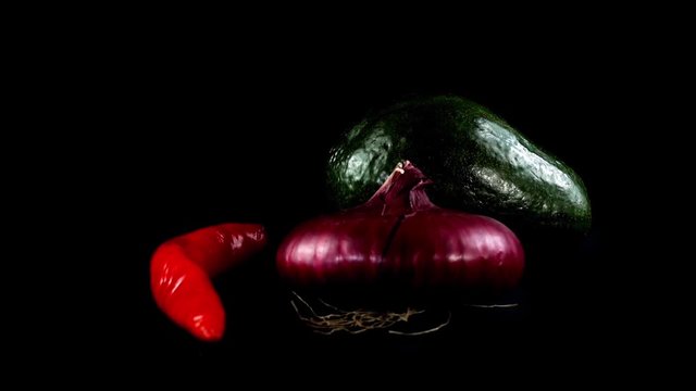 	Avocado, onions and chili pepper on a black background.	Shooting in the movement.