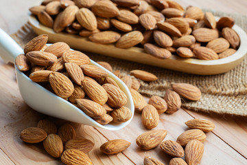 almond nuts in white scoop on wooden table.